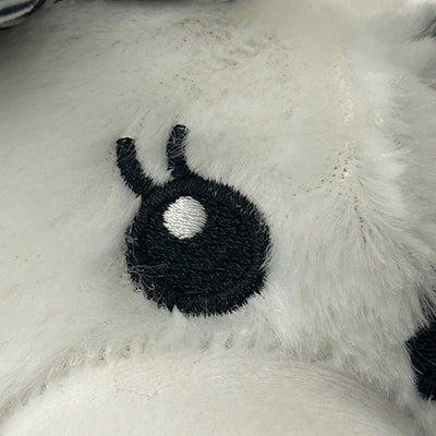 Black fuzzy eyeball with a white centre on a fluffy white surface