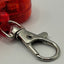 Metallic keychain clip attached to a red dog flasher on a white background