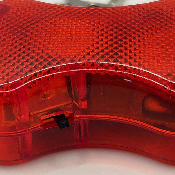 Close-up of the operating button for the red transparent dog flasher on a white background