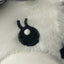 Black fuzzy eyeball with a white centre on a fluffy white surface