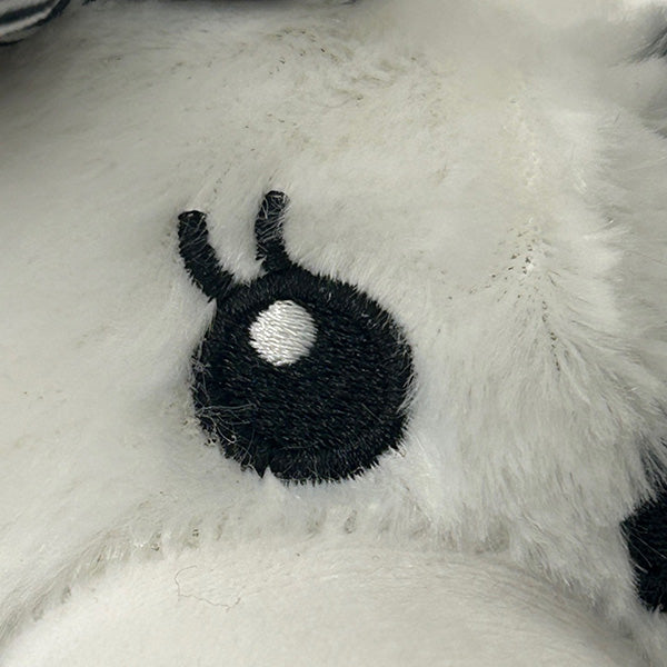 Black fuzzy eyeball with a white centre on a fluffy white surface