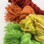 Close-up of colorful yarn skeins in red, orange, green, and yellow on a white background.