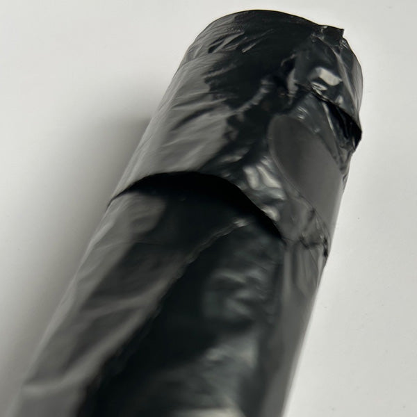 Sealed roll of black doggy bags on white background