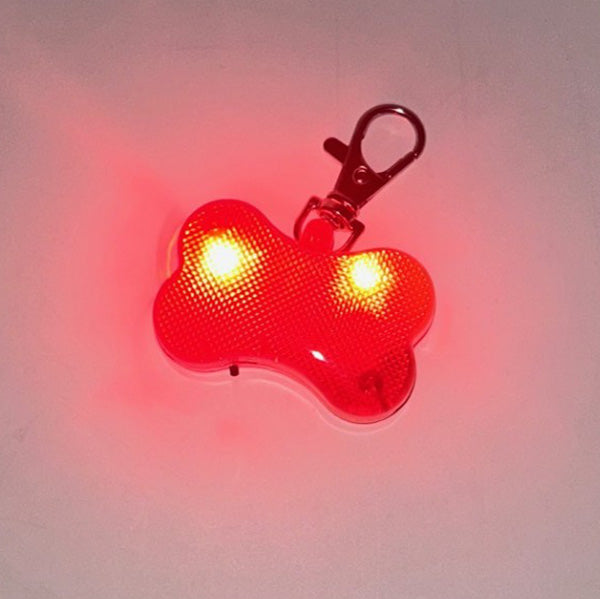 Red bone-shaped LED light with a clip on a gray background